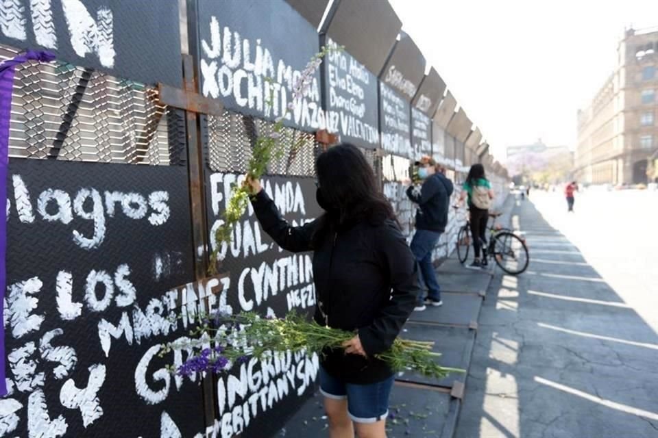 Mujeres colocan flores en las vallas metálicas que rodean Palacio Nacional y que desde anoche tienen nombres de víctimas de feminicidio.