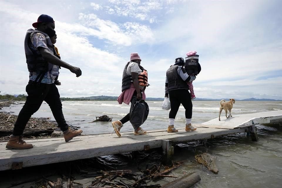 Migrantes haitianos caminan por el muelle en Necoclí, en la costa caribeña de Colombia, para partir en un bote que los llevará a Acandi.