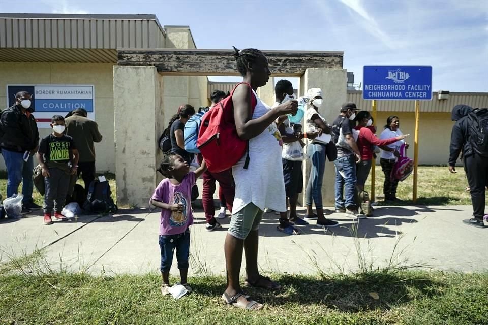 Migrantes en Houston esperan un autobús para ir a un centro humanitario luego de ser liberados.