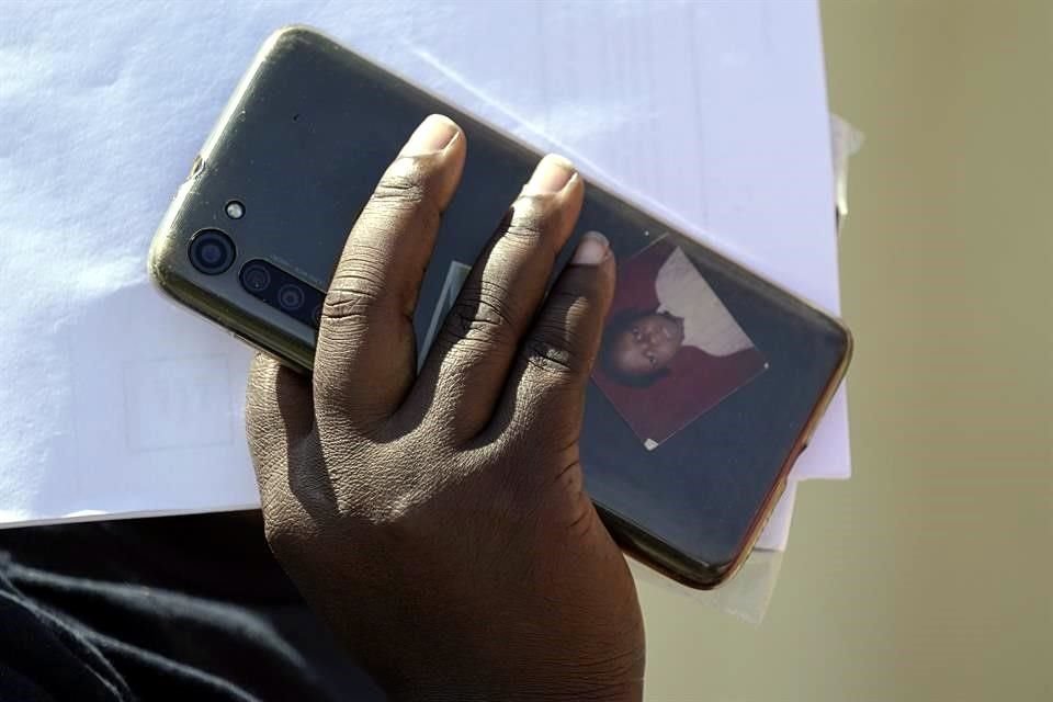 Un migrante haitiano sostiene un celular con una foto dentro de su funda.