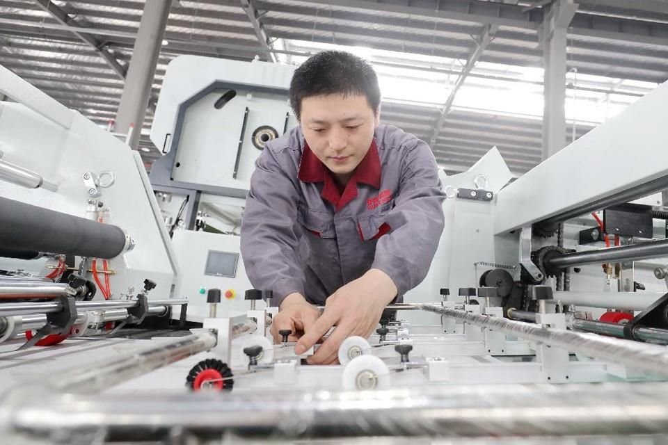 Los trabajadores ensamblan equipos de máquinas de laminación inteligentes en el taller de producción de Zhejiang Kangde New Machinery Manufacturing Co Ltd en Huzhou, provincia de Zhejiang.