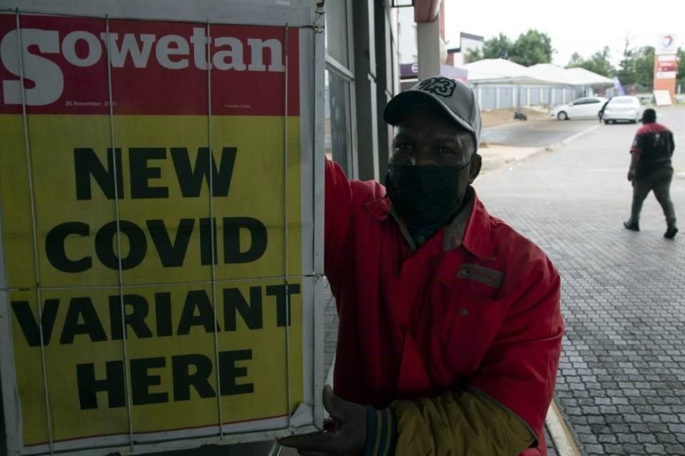 Un hombre en Sudáfrica muestra una plana de un periódico que anuncia la nueva variante del coronavirus.
