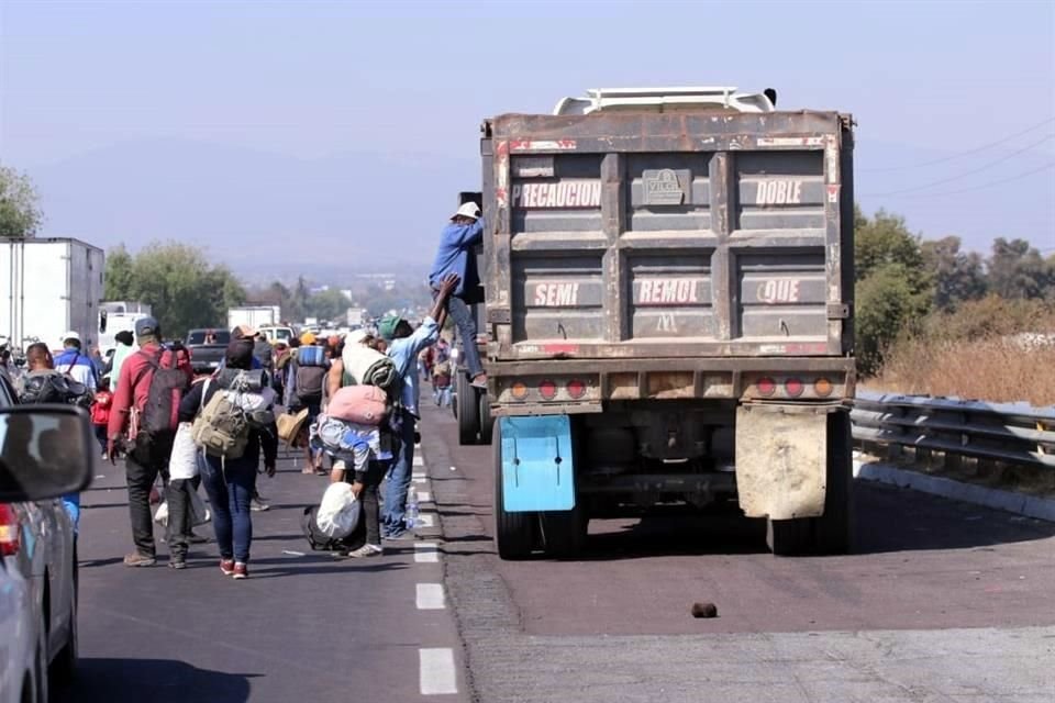 Integrantes de la caravana migrante buscan subir a vehículos.