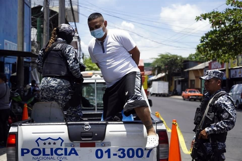 Agentes de la Policía Nacional Civil custodian a una persona detenida durante un operativo de seguridad, en el departamento de San Salvador, El Salvador.