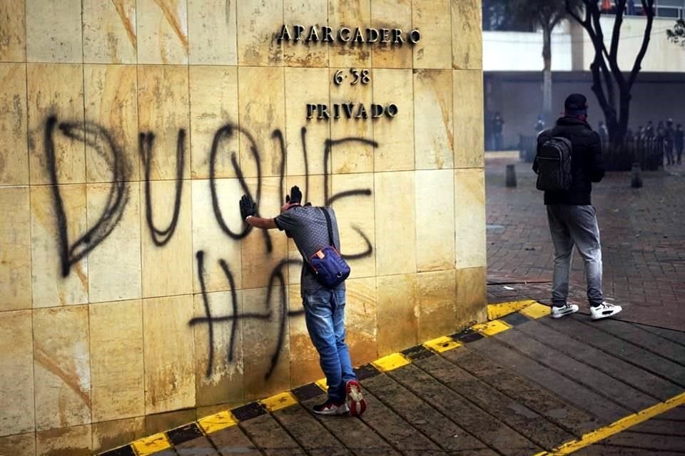 Un joven se sostiene contra una pared pintada con un grafiti contra el Presidente Iván Duque al finalizar una nueva jornada de movilizaciones  en Colombia.