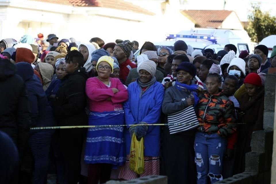 Personas se congregaron a las afueras del bar donde fueron hallados los cadáveres, en East London, Sudáfrica.