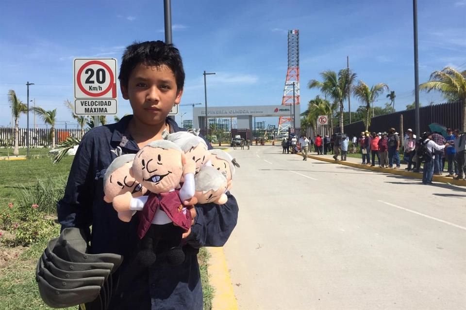 Niño vende muñecos de Andrés Manuel López Obrador afuera de la Refinería Olmeca.