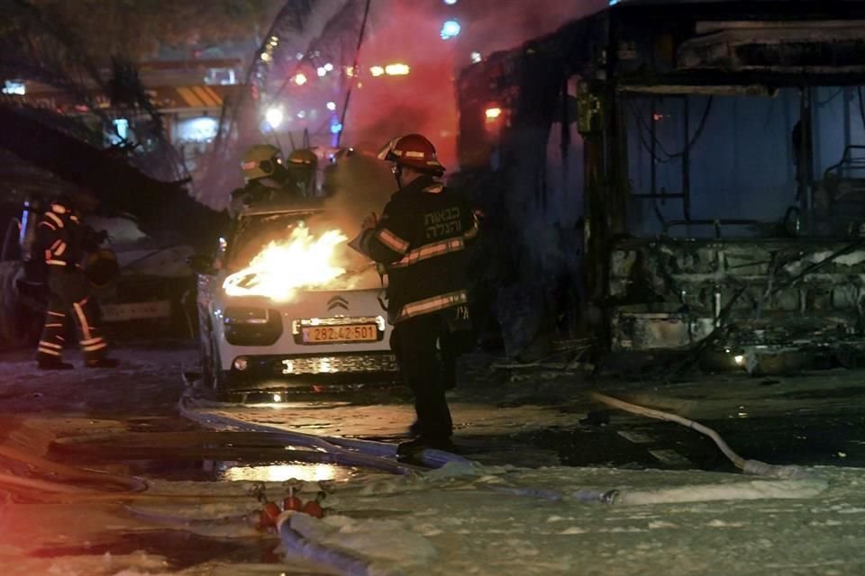 Bomberos israelíes intentan controlar un incendio desatado por un cohete que cayó en un autobús en Tel Aviv.