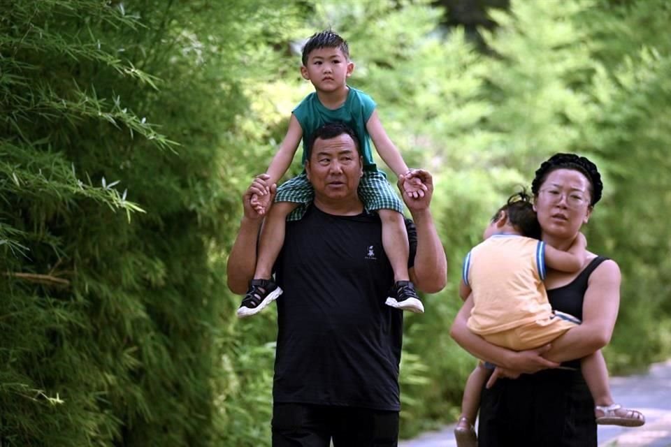 Dos padres chinos caminan cargando a sus hijos mientras pasean por Beijing.