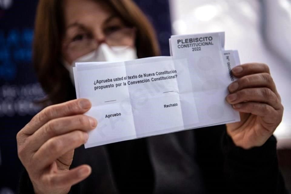 Una trabajadora municipal muestra la boleta que se utilizará mañana en el plebiscito de la nueva Constitución.