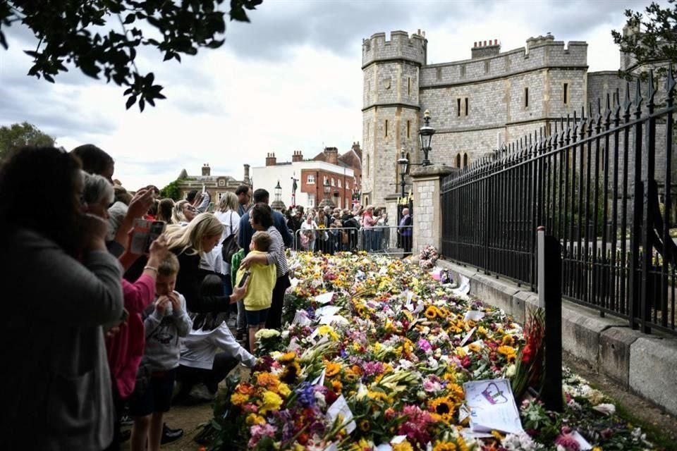 Dolientes dejan flores en honor a Isabel II a las afueras del Castillo de Windsor, donde la monarca será enterrada.