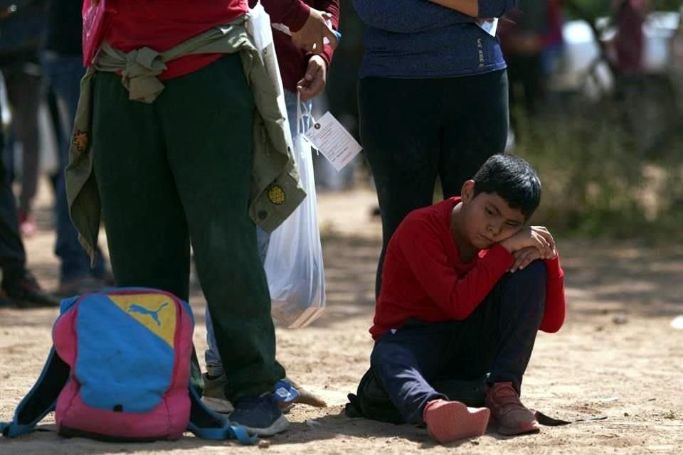 Un niño descansa en el suelo mientras los migrantes esperan a ser procesados por agentes de la Patrulla Fronteriza en Eagle Pass, Texas.