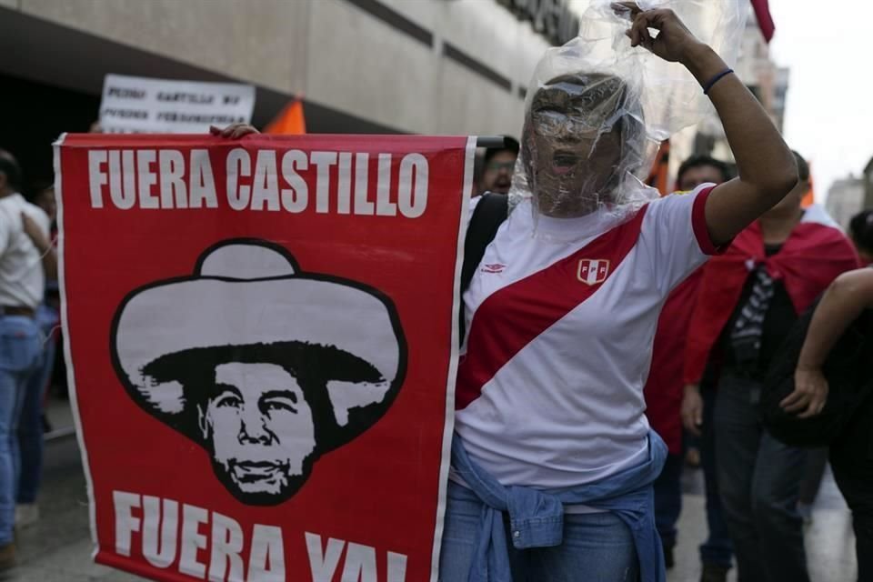 Manifestantes antigubernamentales sostienen un cartel y gritan consignas durante una protesta cerca del palacio de Gobierno en Lima.