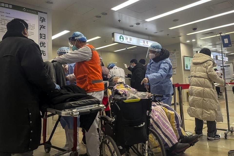 Un trabajador de la salud habla con un paciente en silla de ruedas en el departamento de emergencias de un hospital en Beijing.
