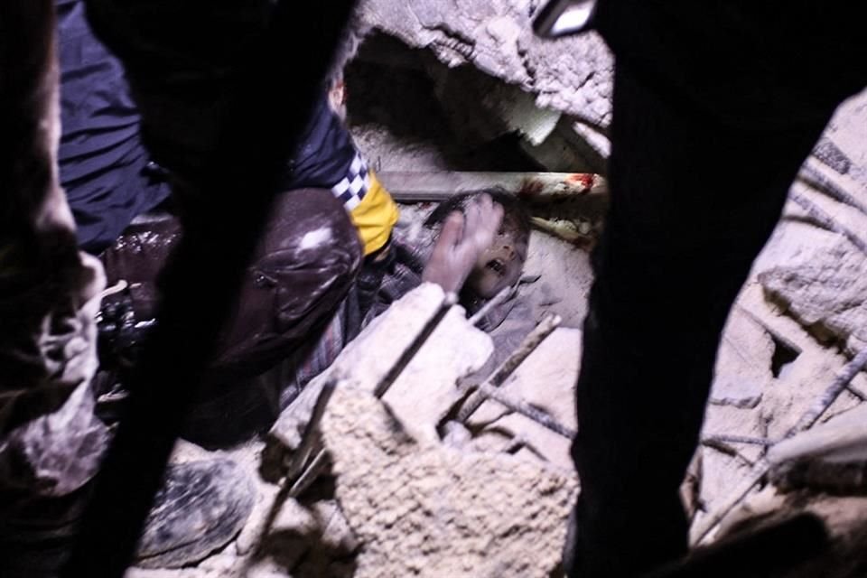 En Alepo, rescatistas trabajan para liberar a un niño atrapado entre escombros.
