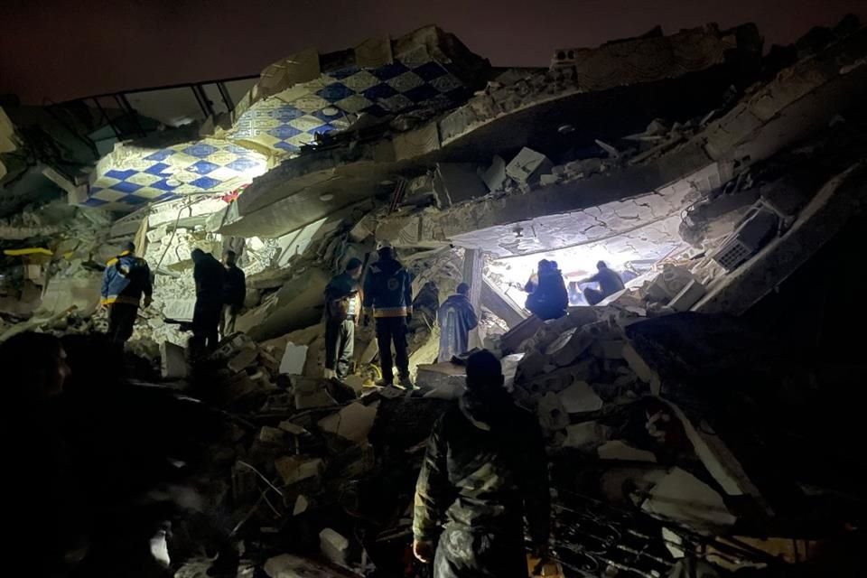 Rescatistas y voluntarios iluminan los escombros para encontrar personas con vida.