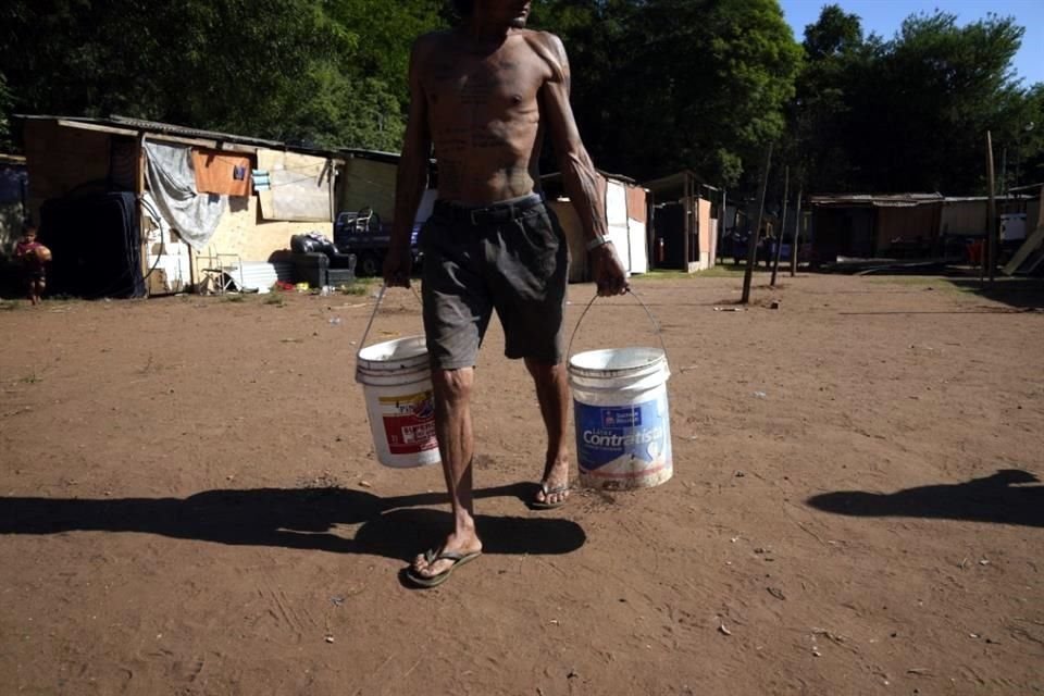 Carmelo Del Valle, que tuvo que abandonar su casa por la crecida del río Paraguay, carga con dos cubos de agua hasta su refugio temporal, en Asunción, Paraguay.
