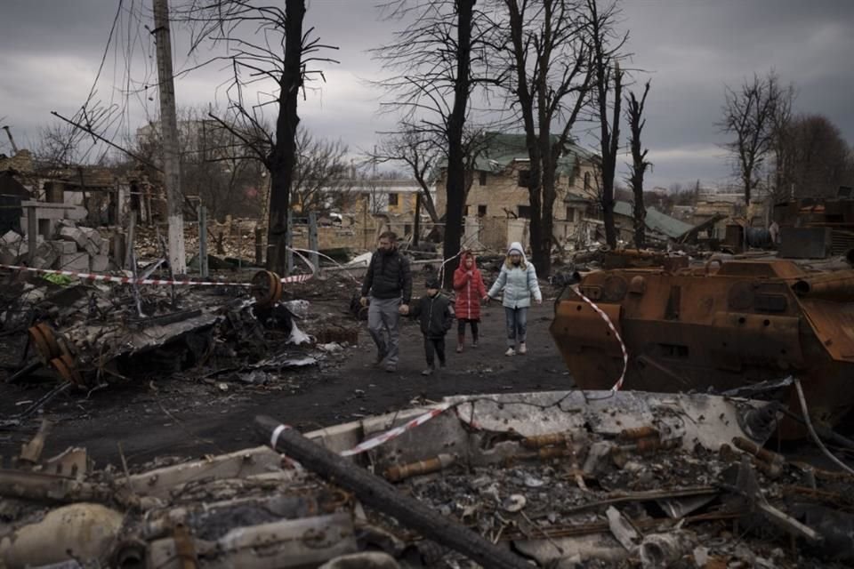 Una familia camina entre tanques rusos destruidos en Bucha, en las afueras de Kiev, Ucrania, el miércoles 6 de abril de 2022.