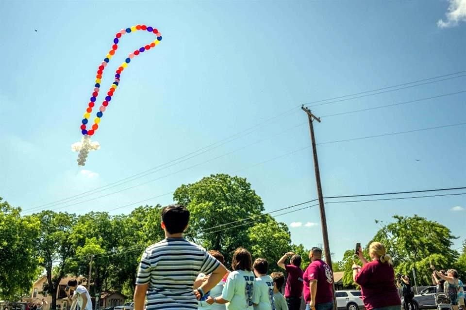 La gente observa cómo se lanzan al aire globos en forma de cruz en un collar en un monumento dedicado a los 19 niños y dos adultos asesinados el 24 de mayo de 2022.