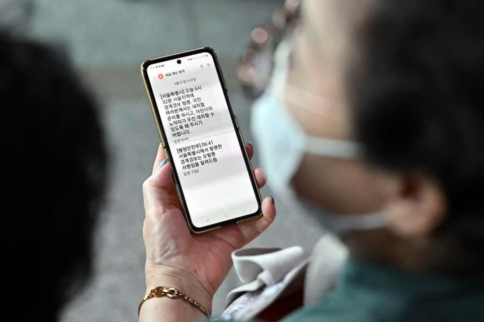 Una mujer muestra su teléfono móvil con un mensaje de texto de advertencia de evacuación de emergencia emitido por la ciudad de Seúl.