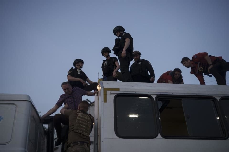 Militares ayudan a residentes a descender de un autobús durante la evacuación de un vecindario inundado en Jersón.