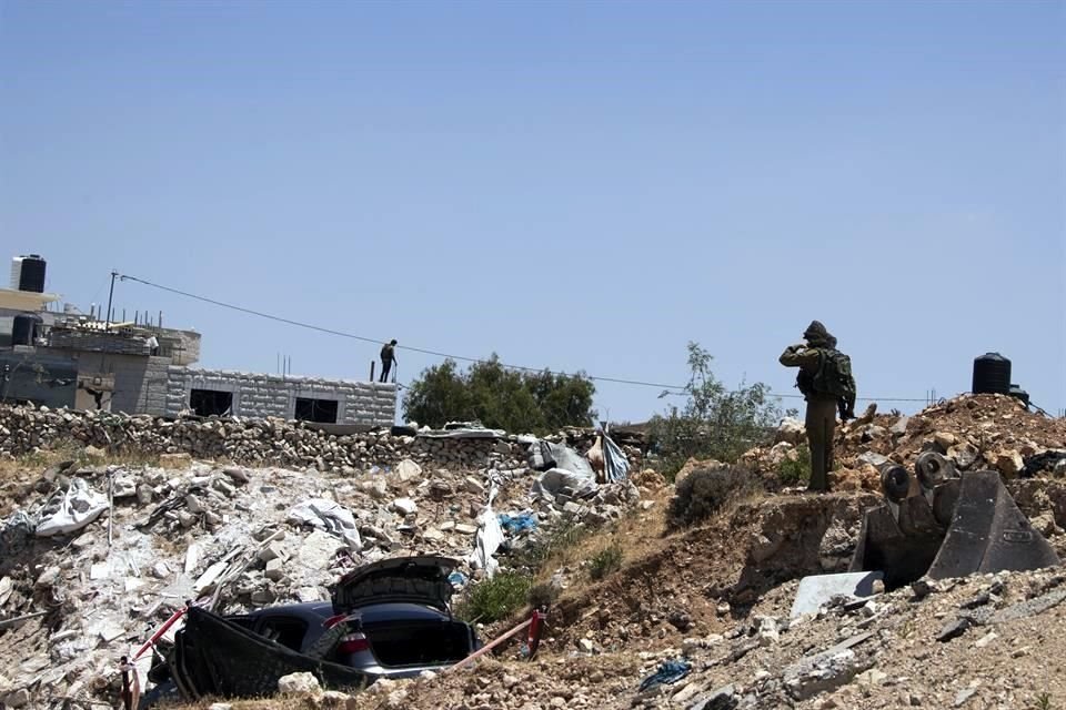 Un soldado israelí cerca del auto presuntamente usado para un ataque, en Cisjordania.