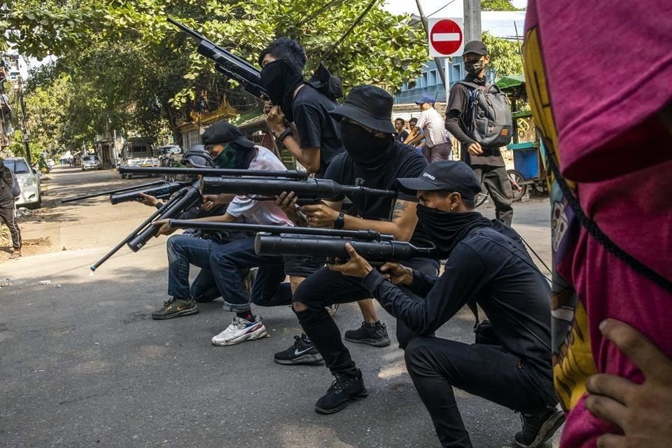 Manifestantes contrarios al golpe apuntan con rifles de aire caseros durante una protesta en Yangón.
