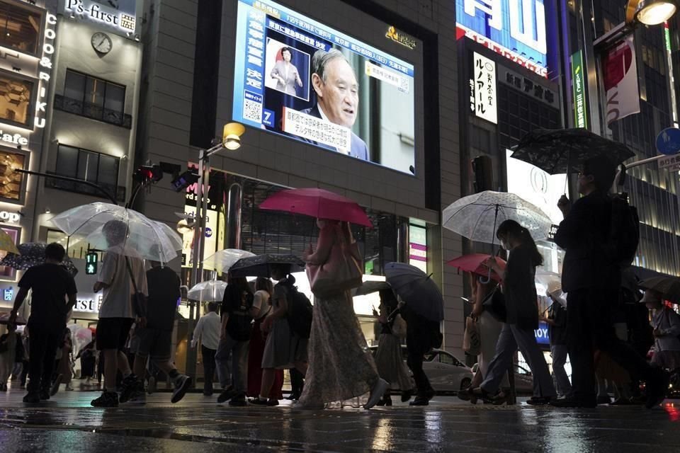 Peatones en Tokio se detienen a ver el anuncio del Primer Ministro Yoshihide Suga de que se amplió el estado de emergencia.