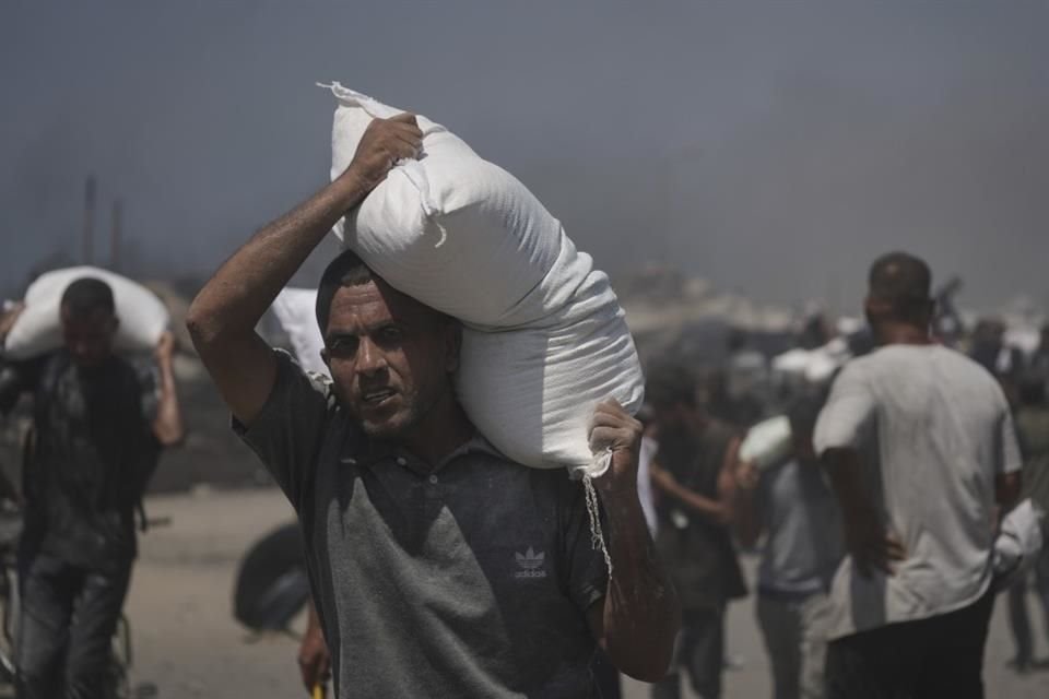 Palestinos cargan sacos de harina transportados por un convoy humanitario que llegó a Ciudad de Gaza desde el norte de la Franja de Gaza, el 27 de julio de 2025.